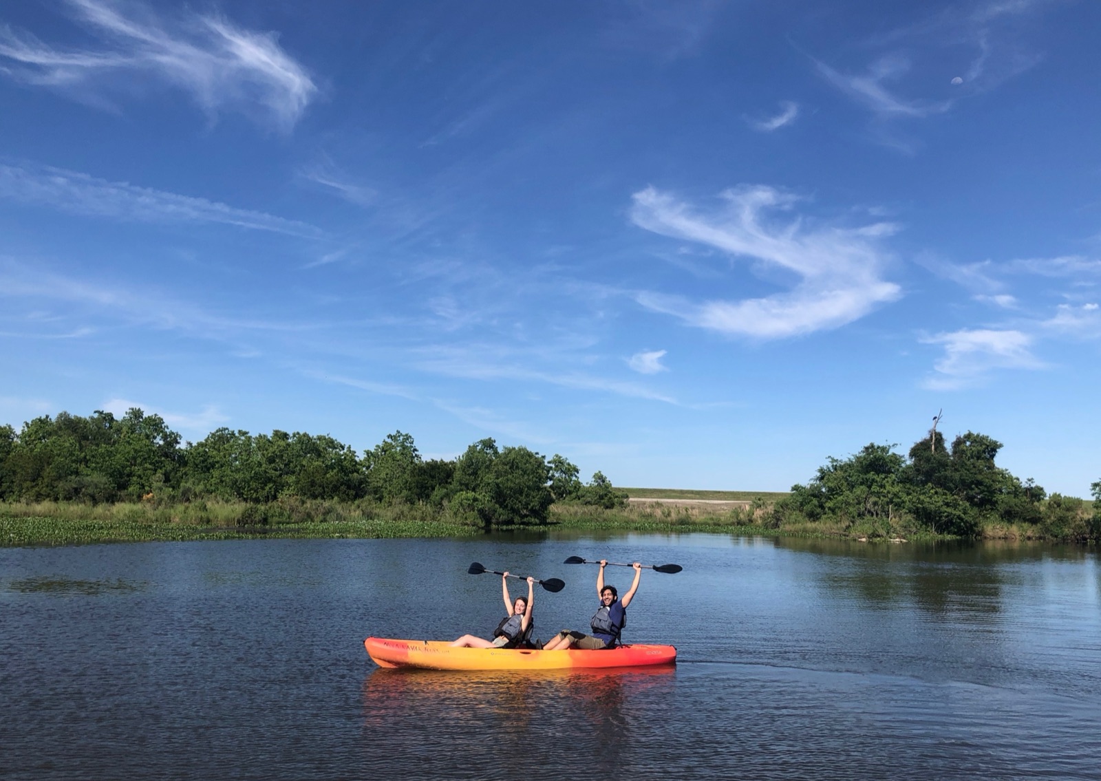 Two paddlers raising their paddles from a tandem kayak on Bayou Bienvenue near New Orleans